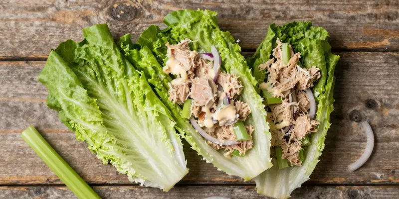 Flat lay, food blog, two crisp iceberg lettuce leaves used as wraps, filled with chunky keto tuna salad (tuna, mayo, celery